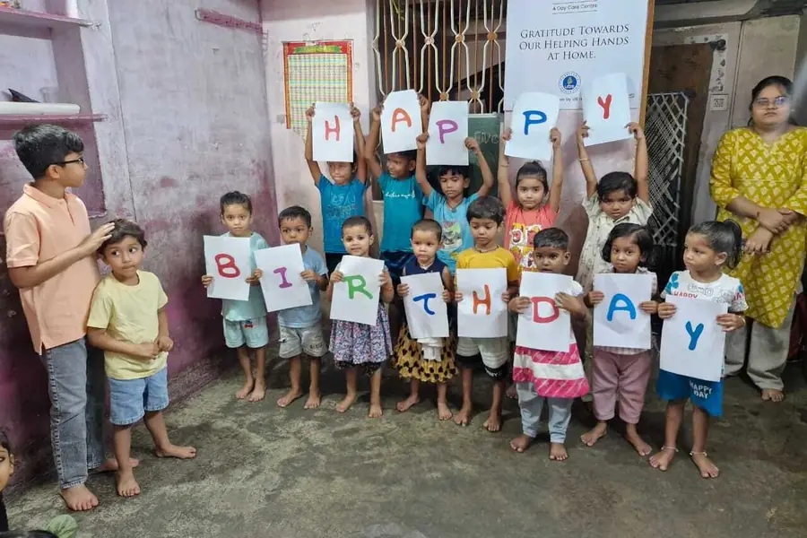 Children holding up paper letters spelling Happy Birthday