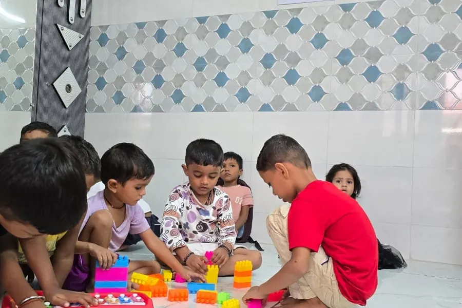 Two children building with coloured blocks on the floor