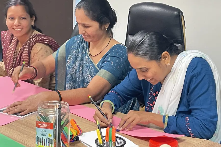 Three women at work on a craft table during a training session